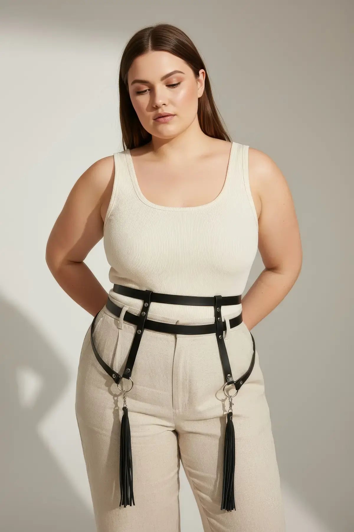 HarnessClub plus-size black vegan leather garter hip belt with leg straps and tassels on model