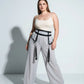 Plus-size black garter hip belt with leg-strap tassels by HarnessClub, shown on a model in a cream top and gray pants.