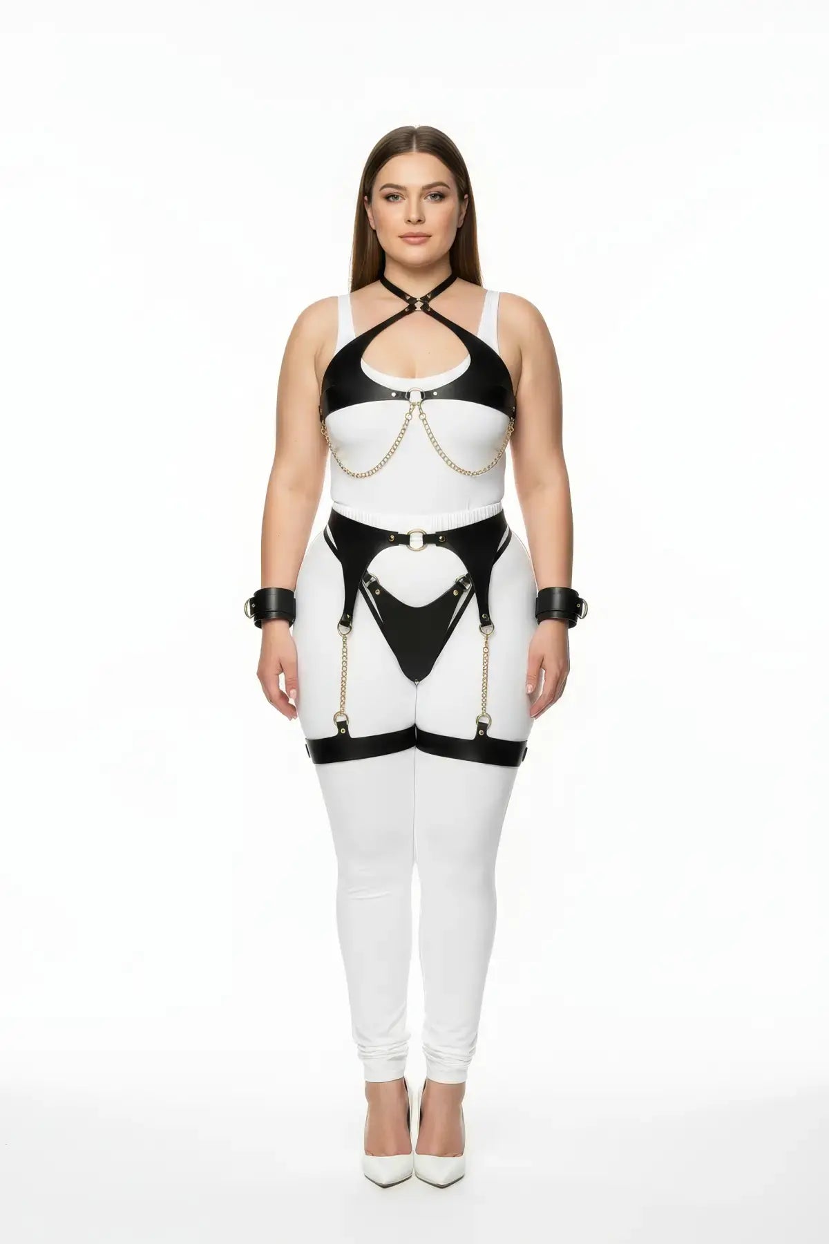 Plus-size black vegan-leather four-piece harness set with gold chains, garter belt, and wrist cuffs.