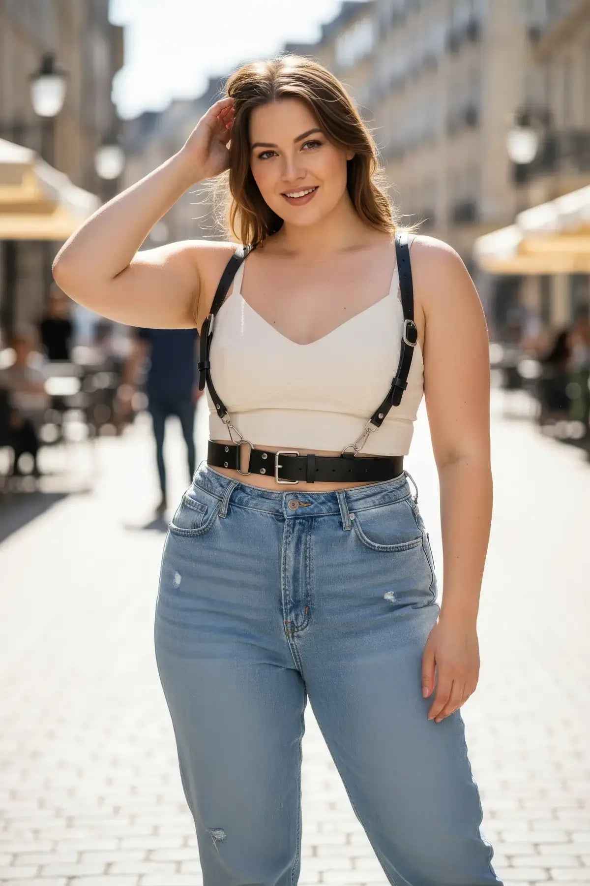 Plus-size black leather harness with O-ring hardware by HarnessClub, worn over a white top.