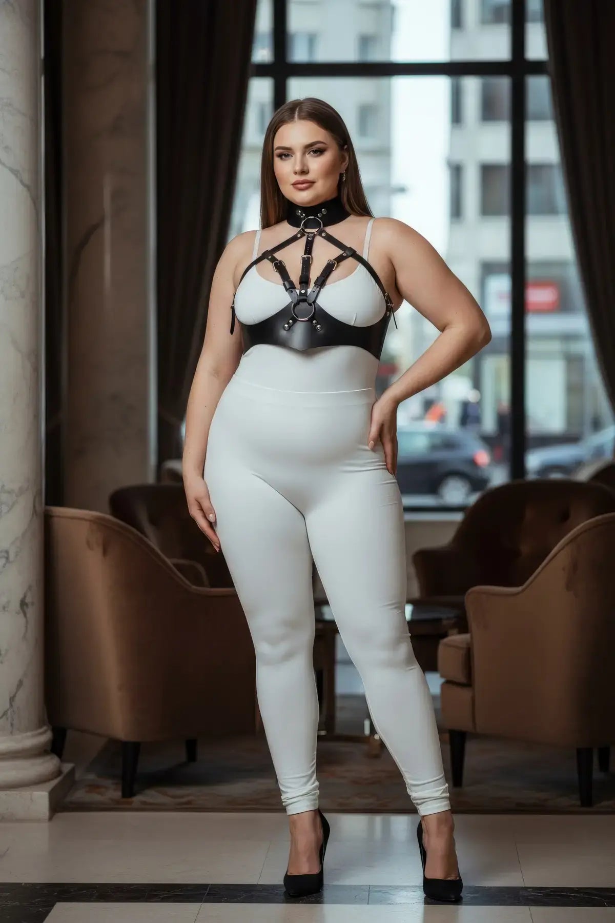 Plus-size black faux leather chest harness set with high collar and metal rings worn over a white bodysuit.