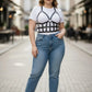 Plus-size black leather body harness outfit worn over a white tee, HarnessClub, with blue jeans.