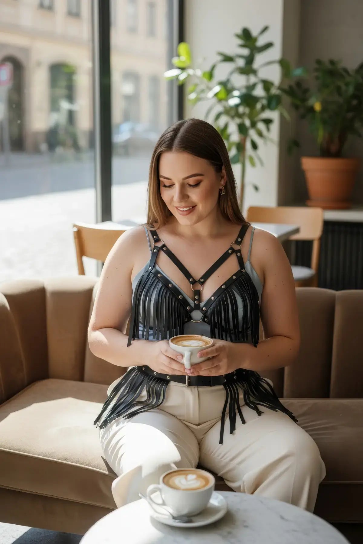 Plus Size Black Leather Fringe Harness by HarnessClub, vegan leather body accessory worn by a woman in a cafe.