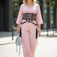Plus size black vegan leather multi-strap corset belt with tassels worn over pink jumpsuit