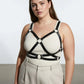 Plus-size black leather harness with O-ring detailing worn over a beige top