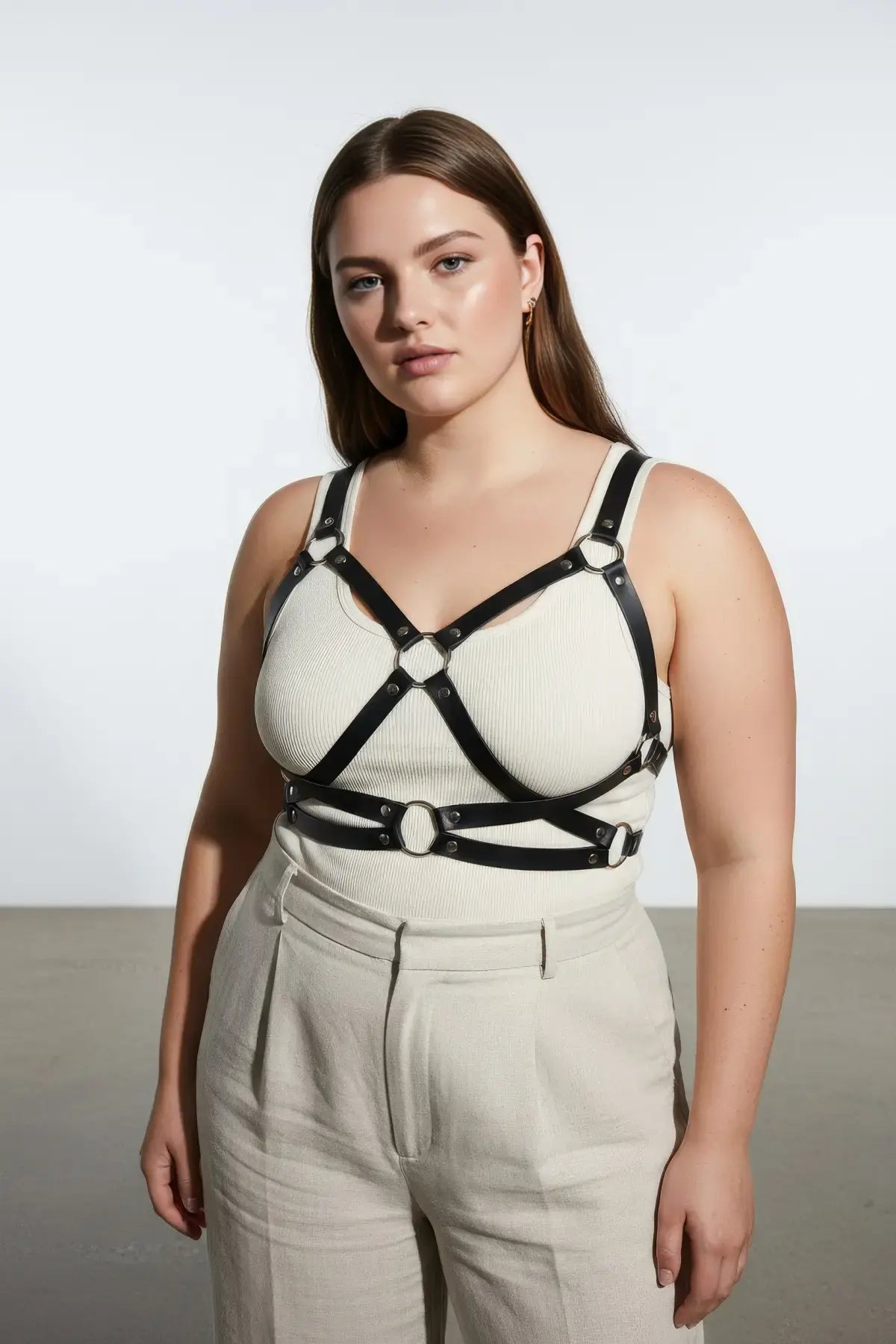 Plus-size black leather harness with O-ring detailing worn over a beige top