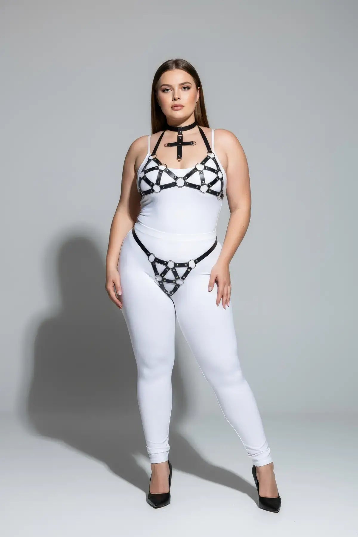 Plus-size black faux-leather O-ring body harness worn over a white bodysuit.