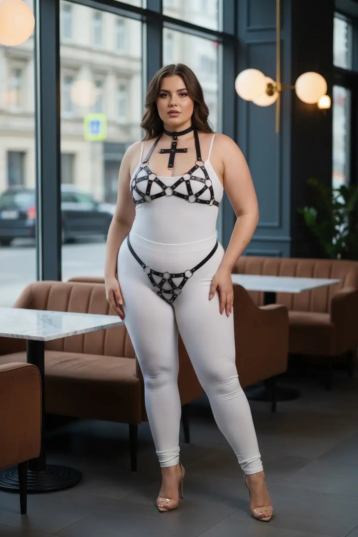 Plus-size black faux-leather O-ring body harness by HarnessClub, worn over a white bodysuit