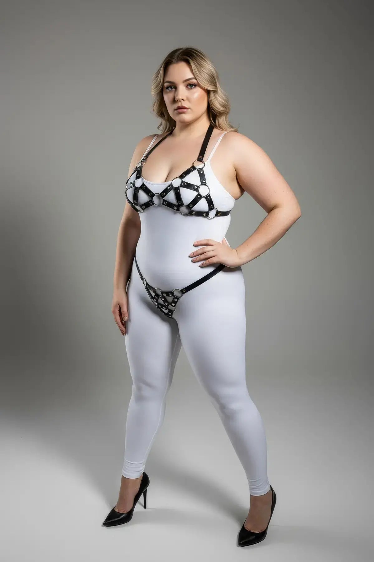 Plus-size black faux-leather O-ring body harness set by HarnessClub, worn over a white bodysuit with metal rings