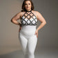 Plus-size black faux-leather O-ring chest harness with lattice straps worn over white bodysuit.