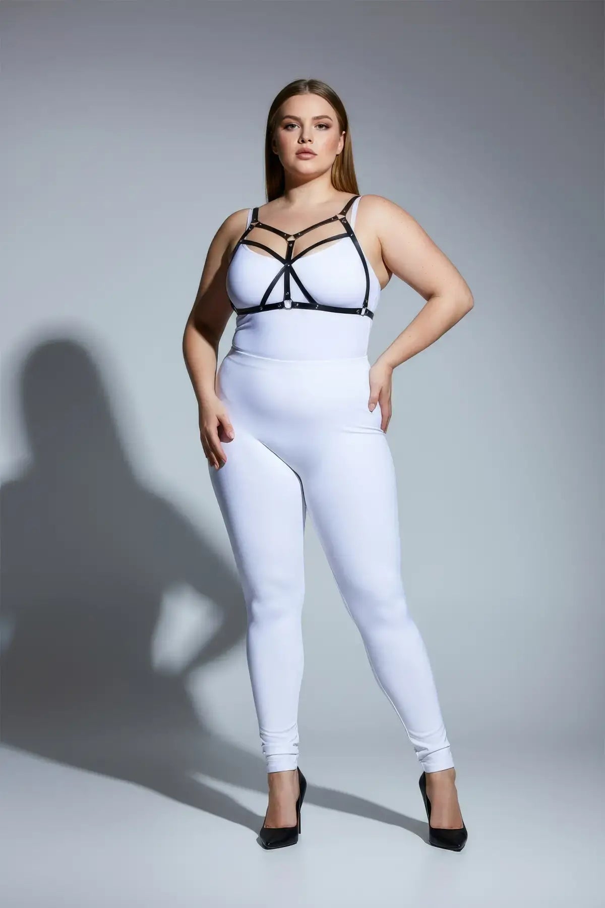Plus-size black faux-leather O-ring harness set worn over white bodysuit, HarnessClub