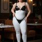 Plus-size black faux-leather O-ring harness set worn over a white bodysuit, HarnessClub.