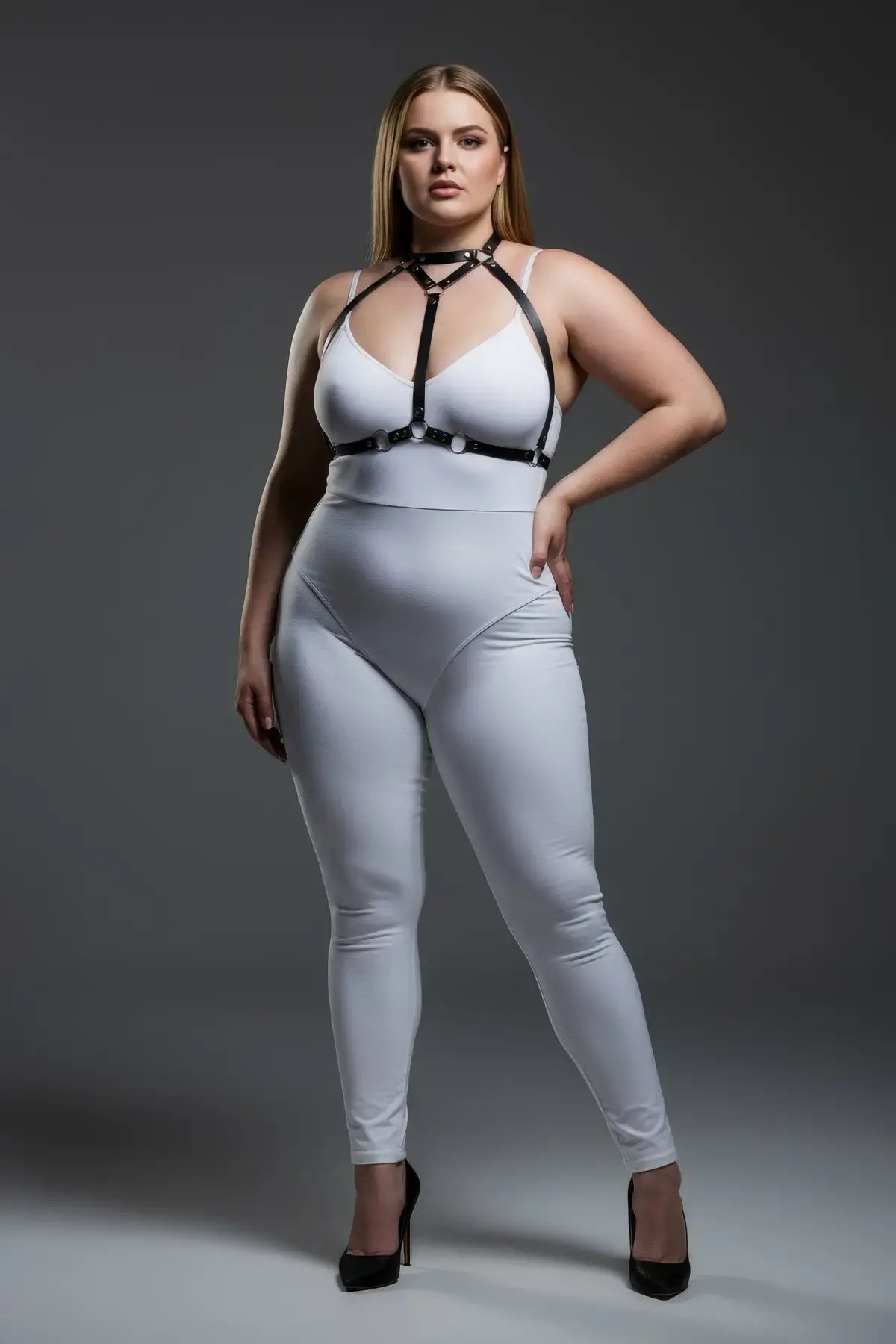 Plus-size black faux-leather O-ring harness worn over a white bodysuit; body accessory
