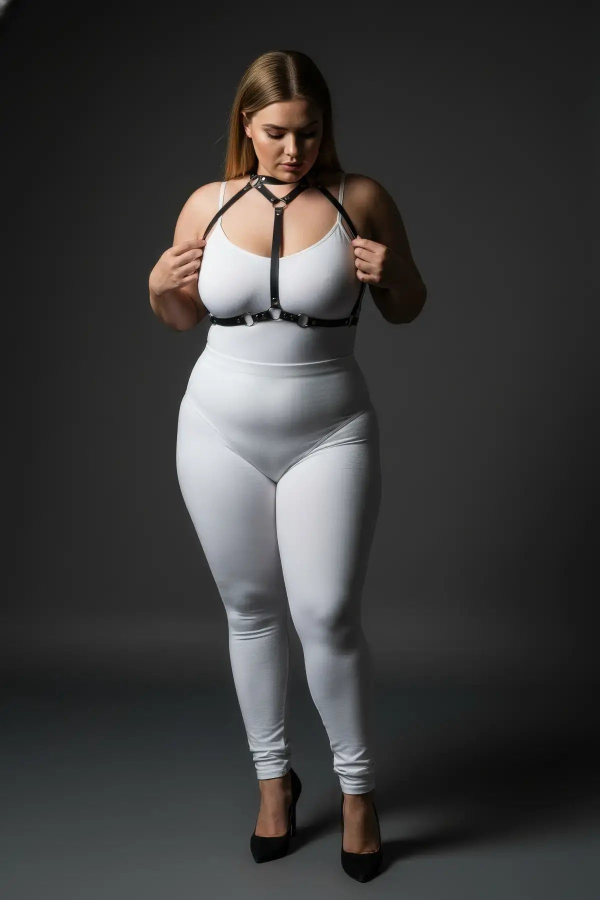 Plus-size black faux-leather O-ring harness worn over a white bodysuit; HarnessClub body accessory
