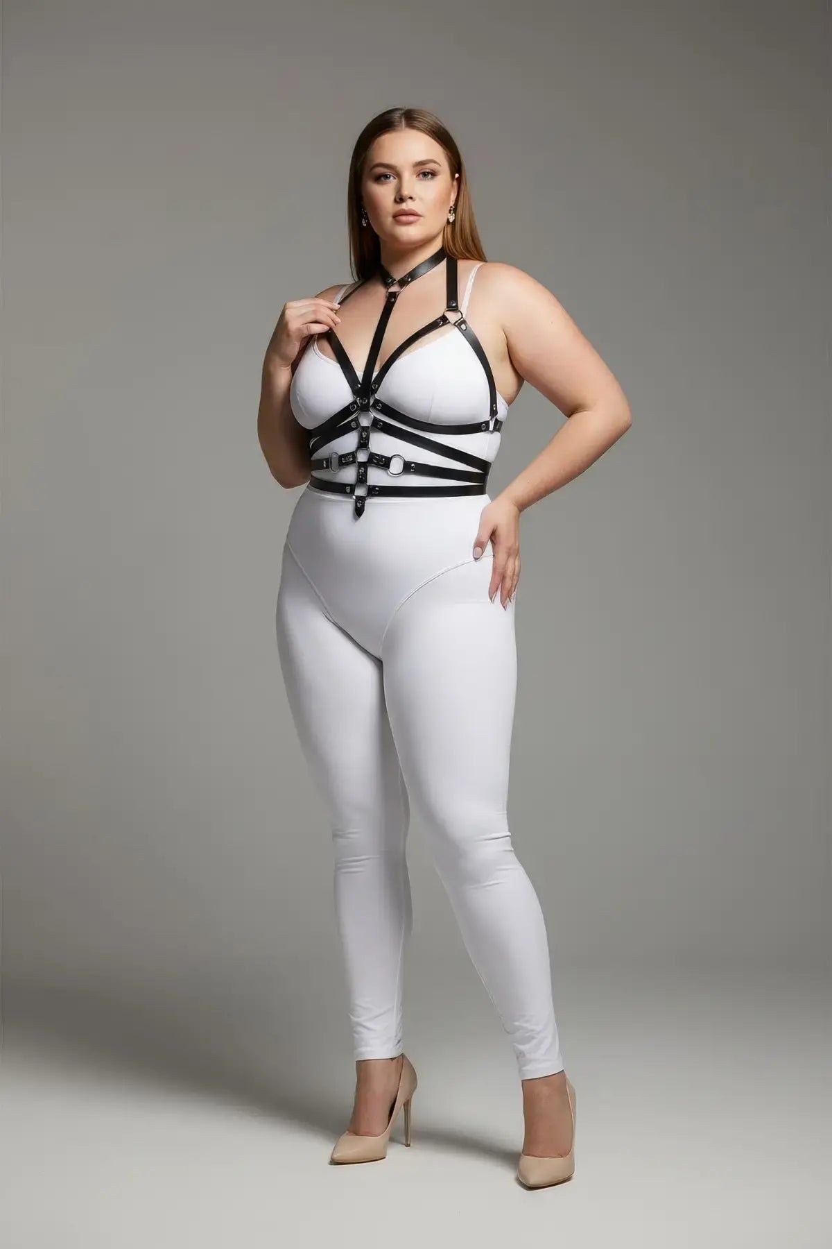 Plus-size black O-ring full-body faux-leather harness worn over a white bodysuit.