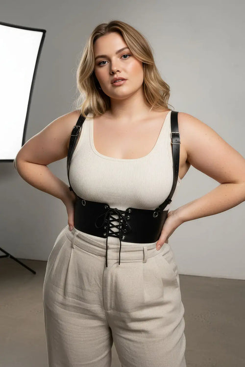 Plus Size Black Shoulder Strap Corset Harness with lace-up front in vegan leather, worn over a cream tank top