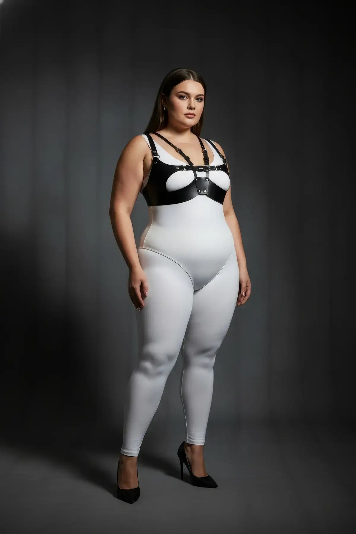 Plus-size black vegan leather chest harness by HarnessClub worn over a white bodysuit.