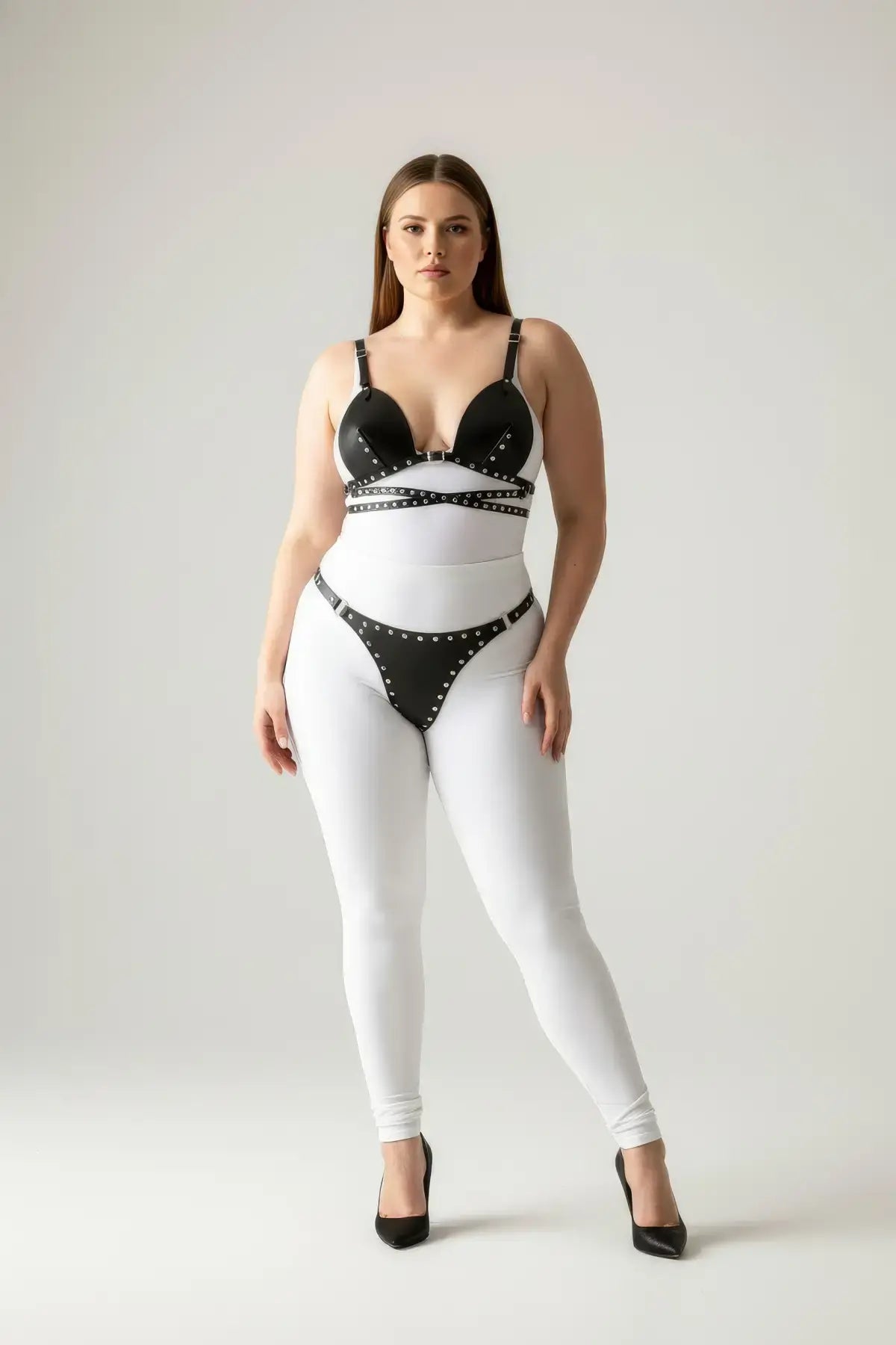 Plus-size black stud-detail faux leather harness set worn over a white bodysuit