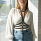 Plus size black studded cage harness in vegan leather worn over a white blouse.