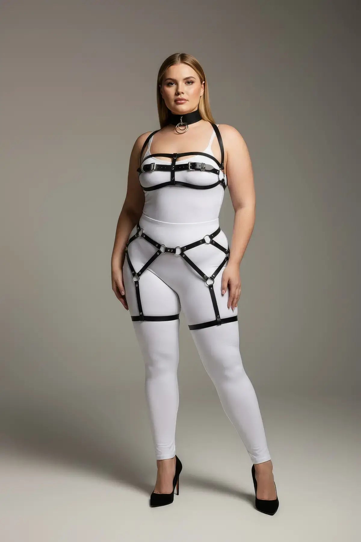 Plus size black suspender garter harness set with faux leather straps and silver hardware on a white bodysuit