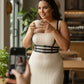 Plus-Size black vegan leather three-band corset harness by HarnessClub worn over a beige ribbed dress