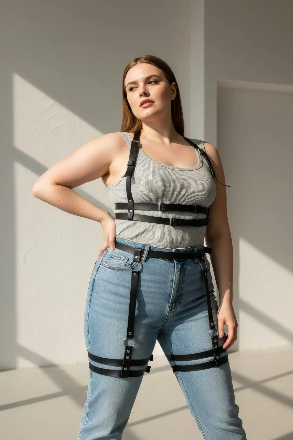 Plus-size black faux-leather garter harness set for upper and lower body worn over a gray tank top