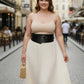 Plus-size black wide-cut corsage body harness belt worn over cream spaghetti-strap dress