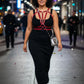 Plus size burgundy V-strap chest harness worn over a black dress; vegan leather body accessory.