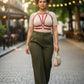 Plus Size Burgundy V-Strap Chest Harness, vegan leather body accessory worn over a beige top by a model on a city street