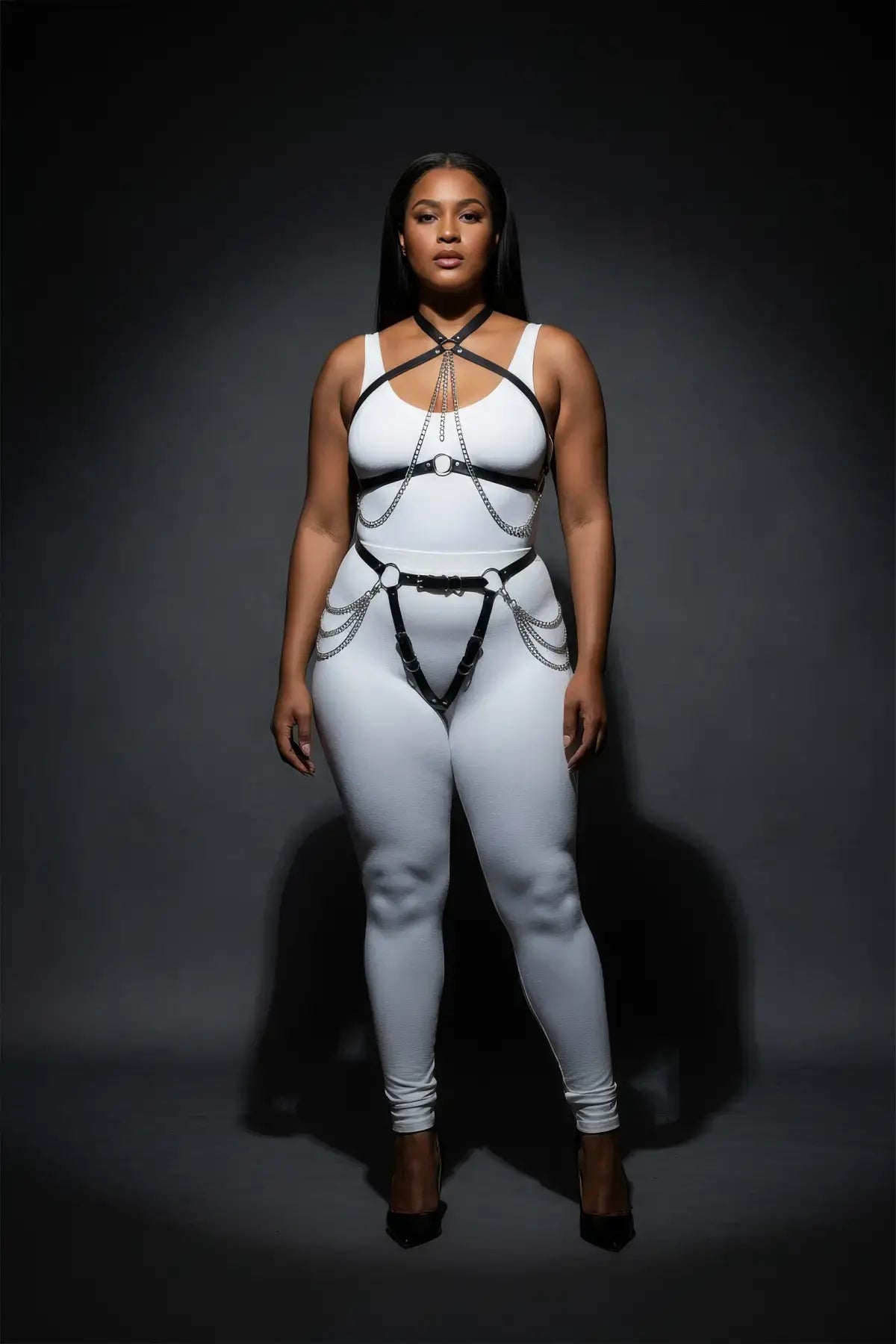 Plus-size vegan leather chain-draped harness set with garter belt on a white bodysuit