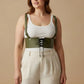 Plus-size khaki corset harness with shoulder straps and lace-up front, worn over a white ribbed tank top.