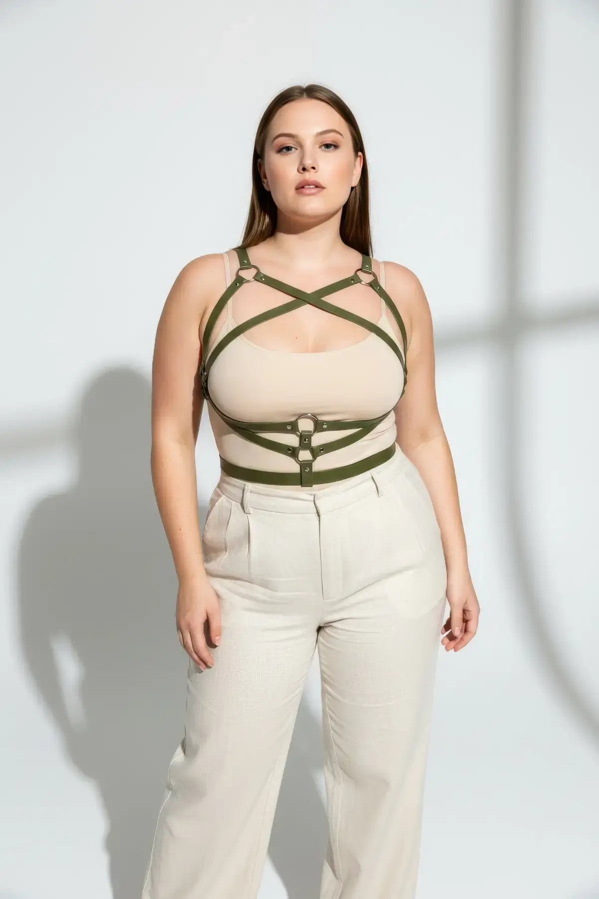 Plus-size khaki leather body harness worn over beige top