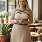 Plus-size khaki leather body harness with crisscross straps worn over a beige top.
