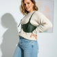 Plus-size khaki vegan-leather shoulder-strap corset harness over cream knit sweater