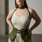 Plus-size khaki vegan-leather suspender corset harness with choker and hip flaps worn over a white tank