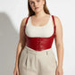 Plus-size red vegan-leather lace-up corset harness worn over a white tank top.