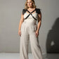 Plus-size leather body harness with shoulder tassels, black cross-strap design worn over a white top.