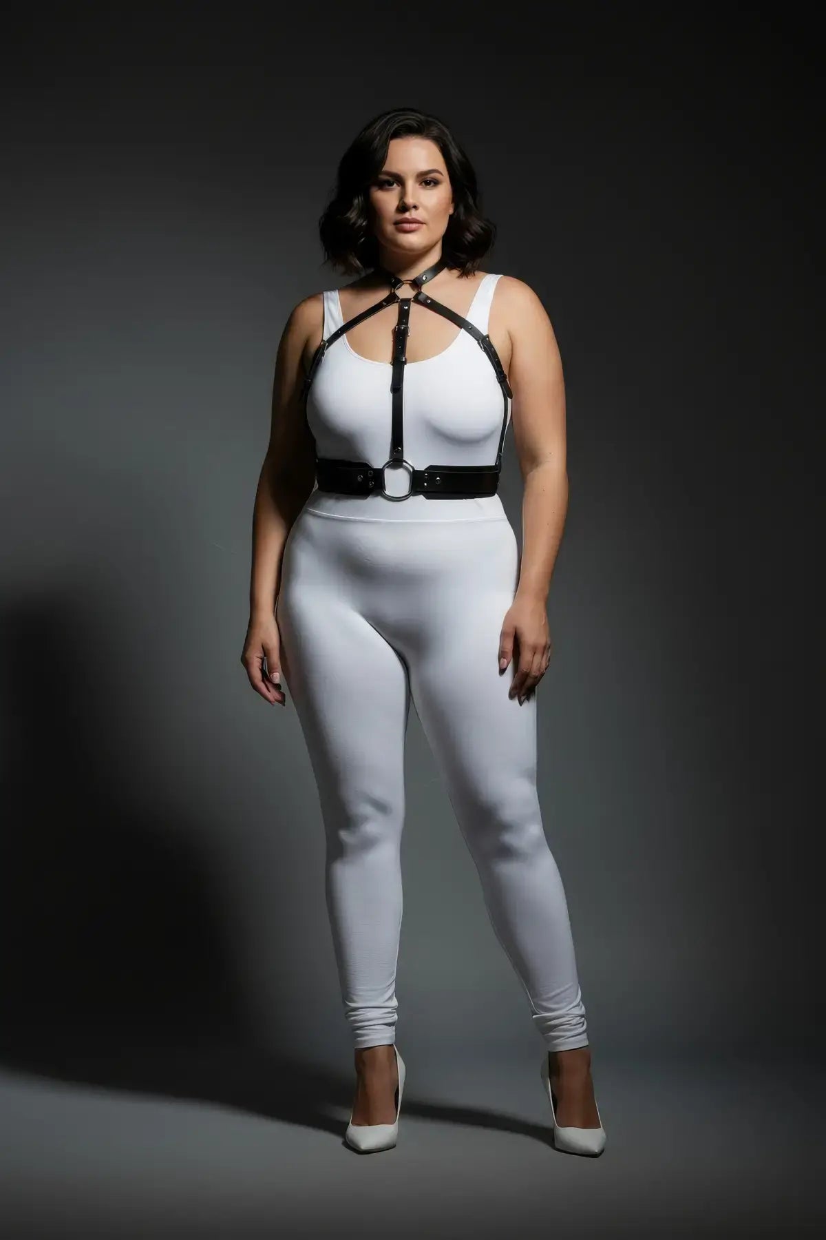 Plus-size minimalist chest harness with choker collar and waist belt in black vegan leather, worn over a white bodysuit.