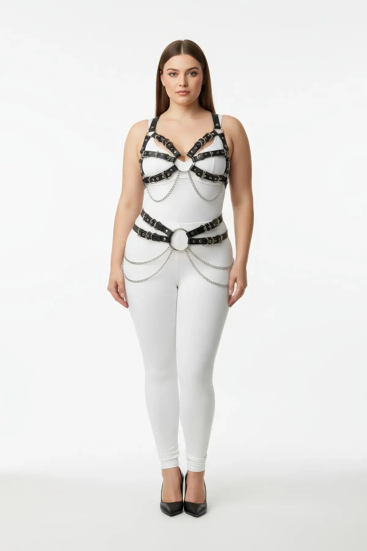 Plus size multi-buckle chest harness with chain-drape waist belt in vegan leather worn over a white bodysuit