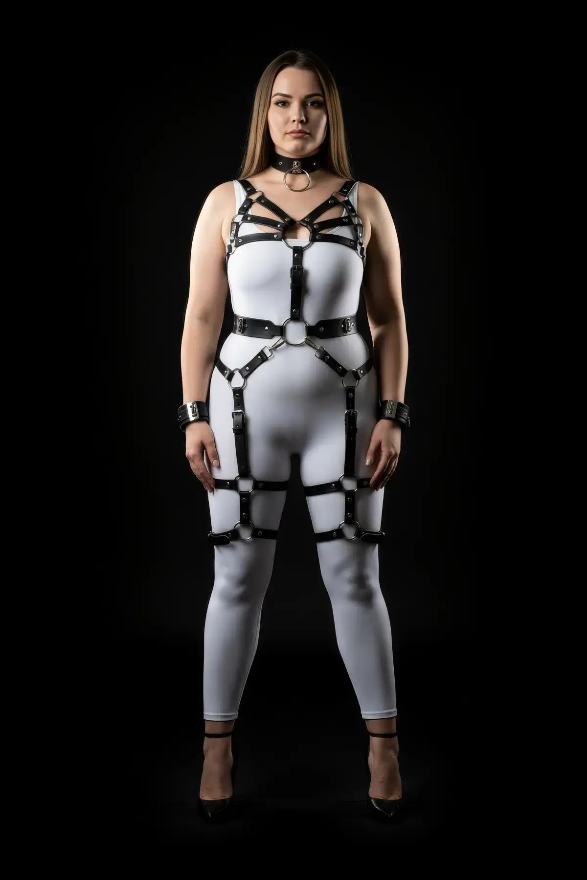 Plus-size vegan-leather multi-strap body harness with wrist cuffs and garter worn over a white bodysuit