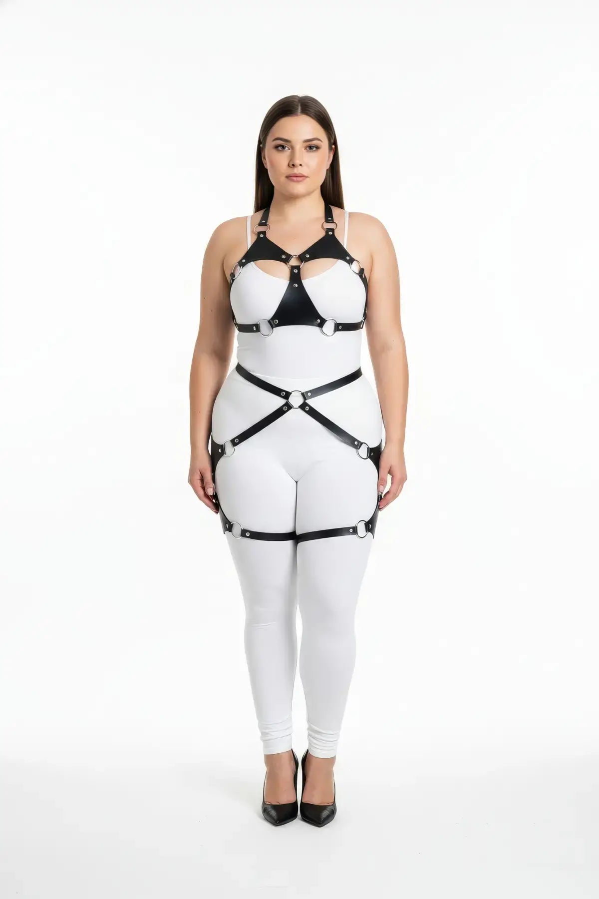 Plus-size O-ring bralette harness with crossover hip garter; black vegan leather straps over a white bodysuit.