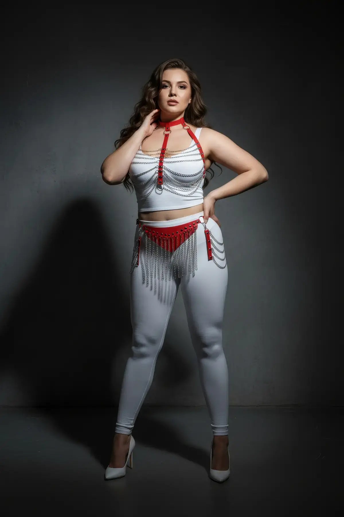 Plus-size red chain bib and chain-fringe belt harness set in vegan leather, shown over white outfit.