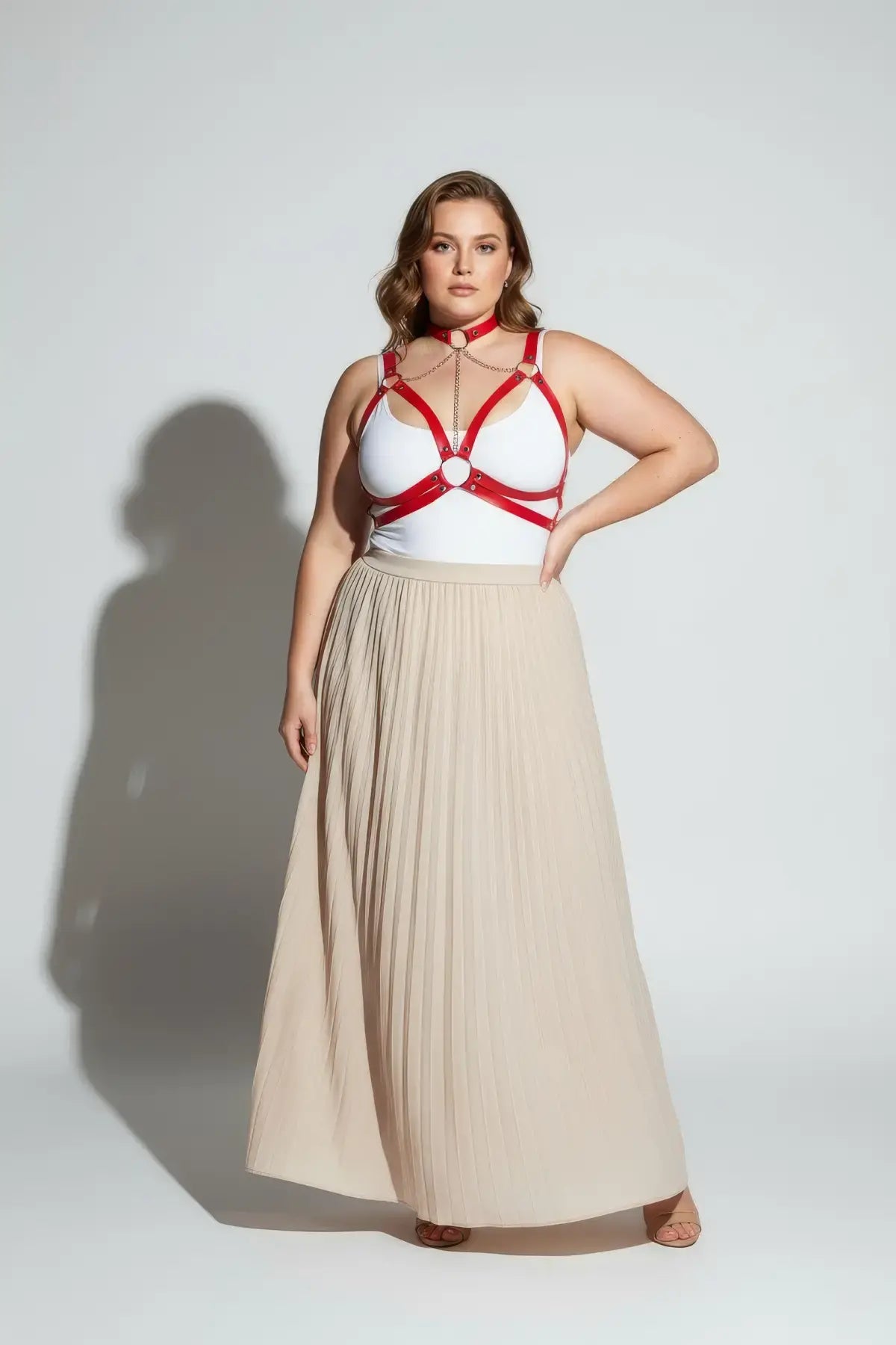 Plus Size Red Chain Cage Chest Harness, vegan leather body accessory worn over a white top with beige pleated skirt
