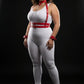 Plus-size red vegan leather chest harness and two cuffs set by HarnessClub, with silver chain detail worn over bodysuit.