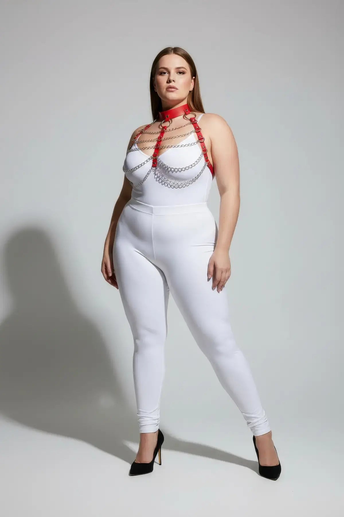 Plus-size red chain-detail faux leather chest harness by HarnessClub worn over white bodysuit.
