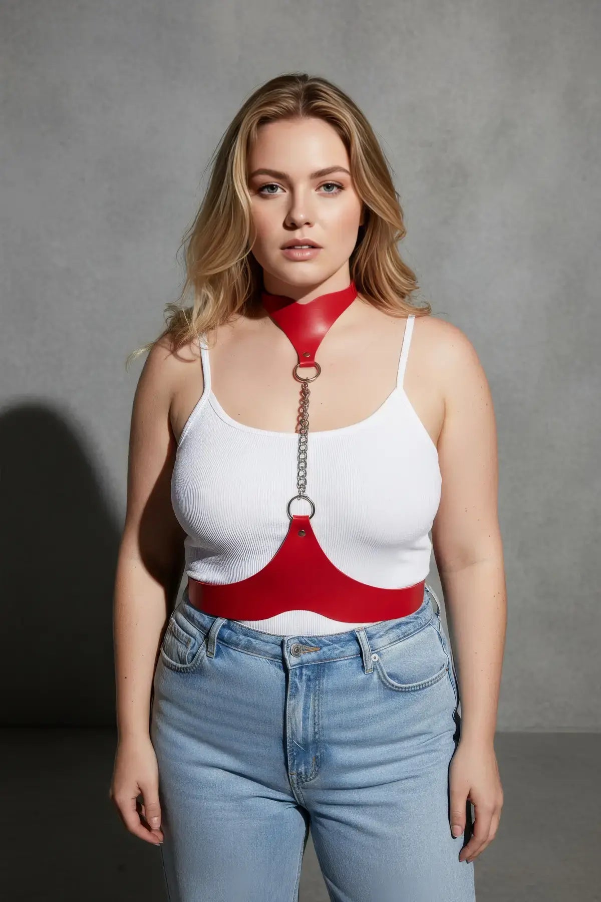 Plus size red leather body harness with chain detail worn over a white tank top