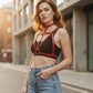 HarnessClub plus-size red choker bralette with V-cross vegan leather body harness worn over a black top.