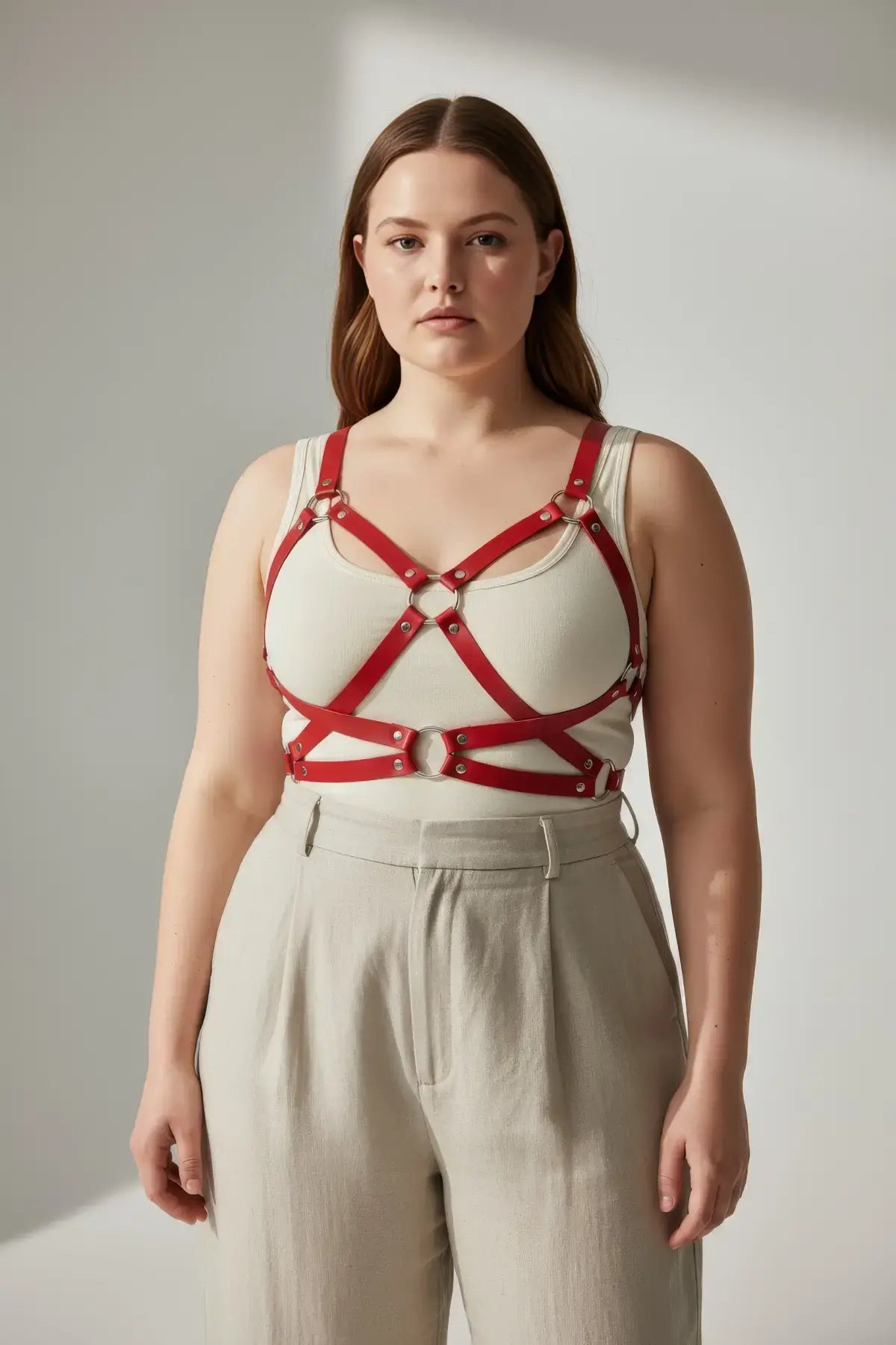 HarnessClub plus-size red leather body harness with corset-detail straps and metal rings.