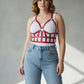 Plus-size red leather corset-style body harness worn over a white tank top and jeans.