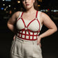 Plus-size red leather corset-style body harness worn over a cream tank top
